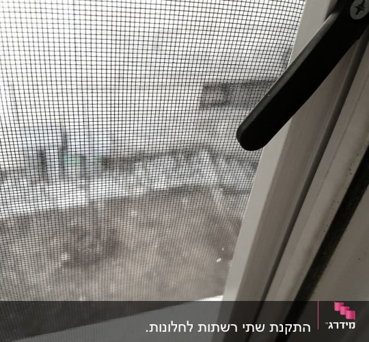 מסגרת אלומיניום עם ידית שחורה ליד חלון רשת